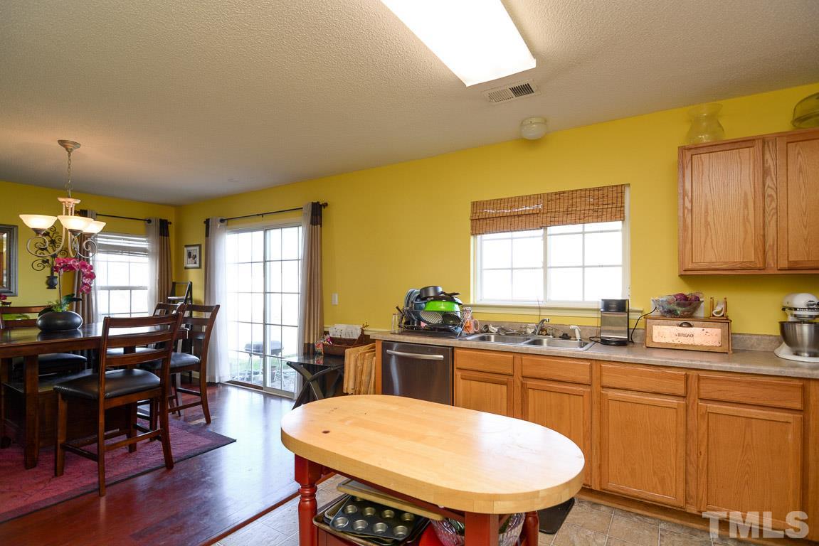 3677 Marshlane Way Raleigh, NC 27610 - Photo 12 of 24 a kitchen with a sink a stove a dining table and chairs
