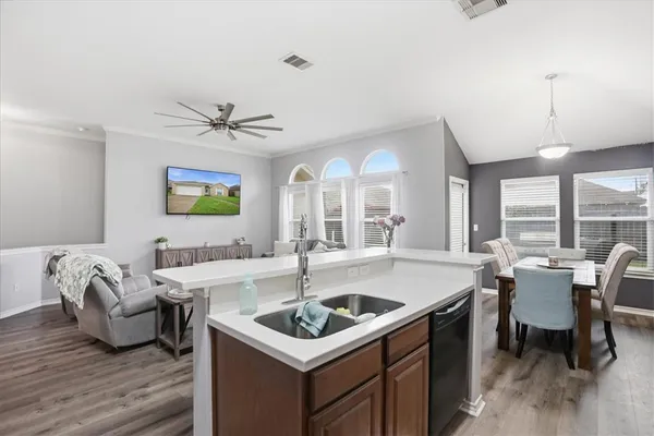 a kitchen that has a sink and a stove with wooden floor
