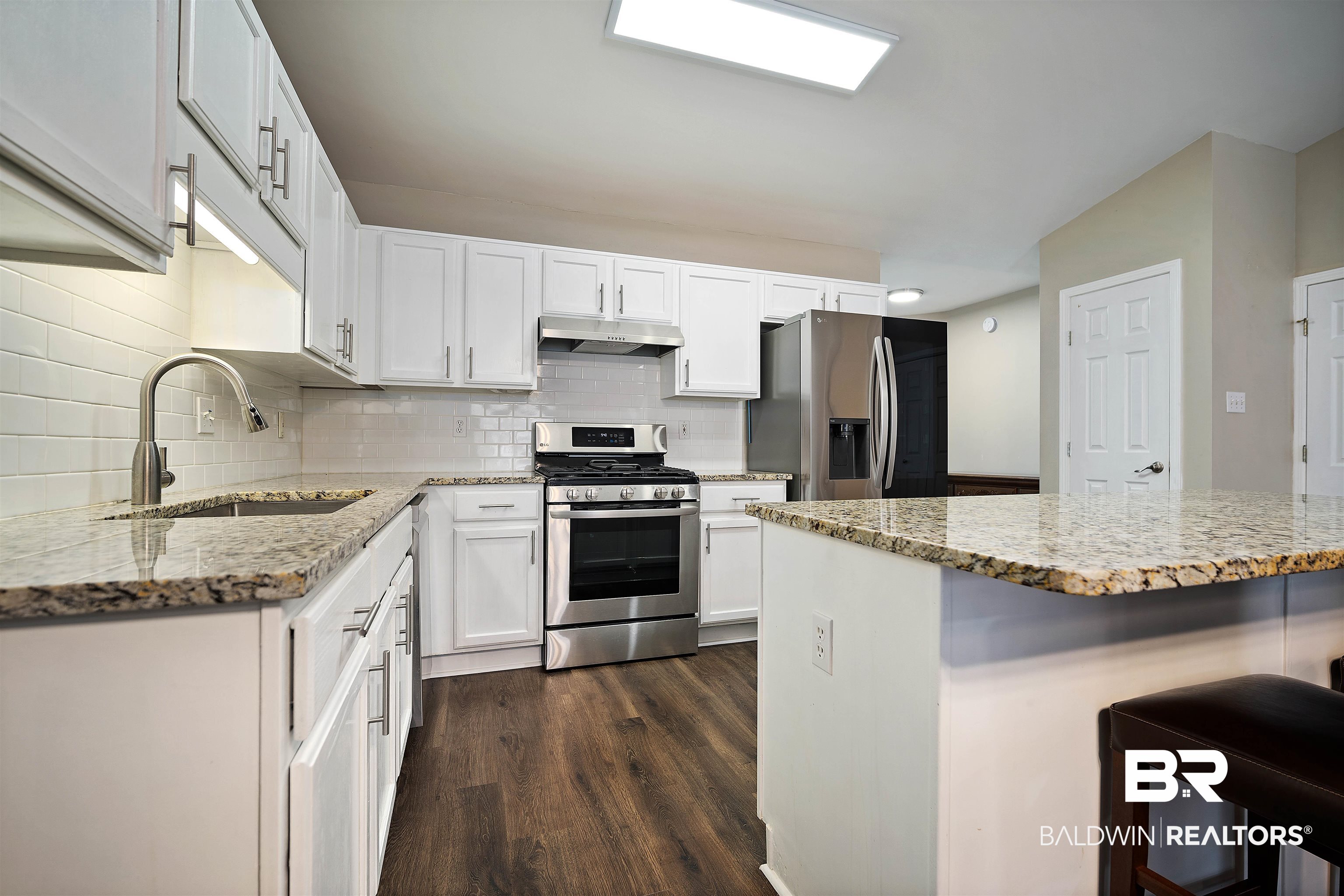628 Spring Lake Court Mobile, AL 36695 - Photo 11 of 25 Kitchen featuring a breakfast bar, sink, white cabinetry, light stone counters, and appliances with stainless steel finishes