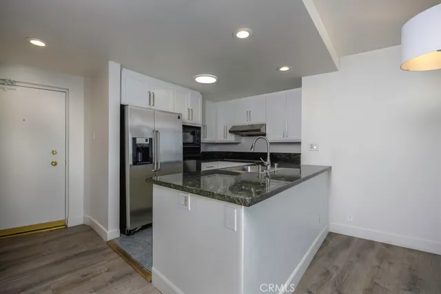 a kitchen with stainless steel appliances granite countertop a sink a stove a refrigerator and a microwave