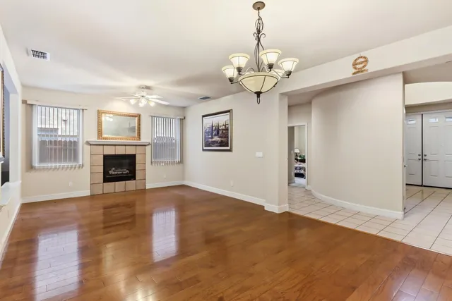 a view of an empty room with wooden floor and a kitchen