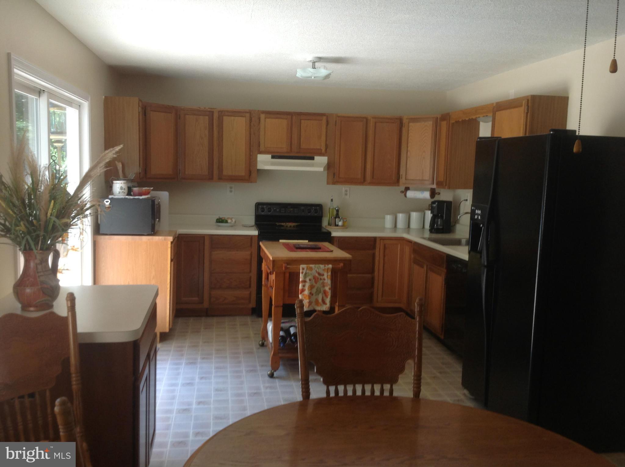 50295 Fresh Pond Neck Road Ridge, MD 20680 - Photo 7 of 10 a kitchen with a refrigerator a stove a sink dishwasher with a dining table and chair