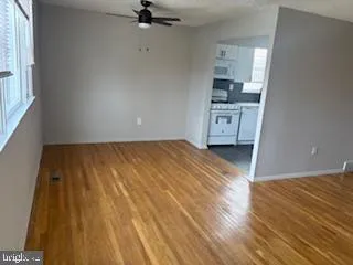 a view of a big room with wooden floor and kitchen