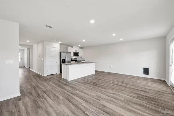 a view of kitchen with kitchen island wooden floor center island and stainless steel appliances
