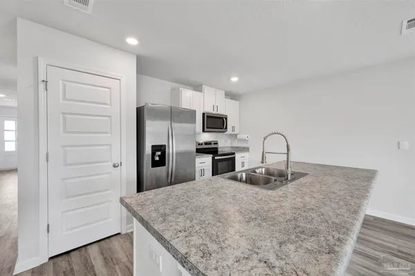 a kitchen with granite countertop a refrigerator and white cabinets