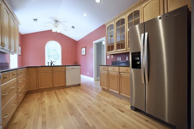 a kitchen with stainless steel appliances granite countertop a refrigerator a sink dishwasher and a oven with wooden floor