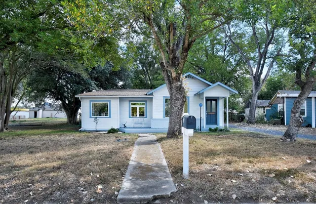 a front view of a house with a yard and trees