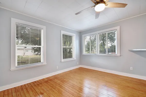 a view of an empty room with wooden floor and a window