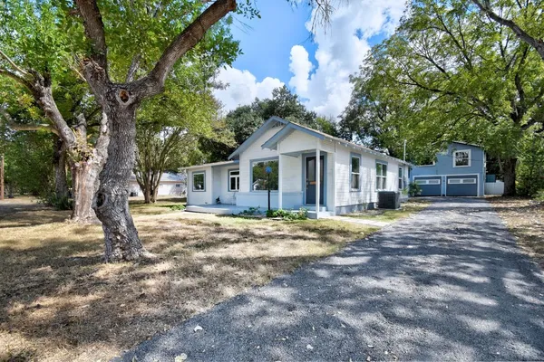 a front view of a house with a garden and trees