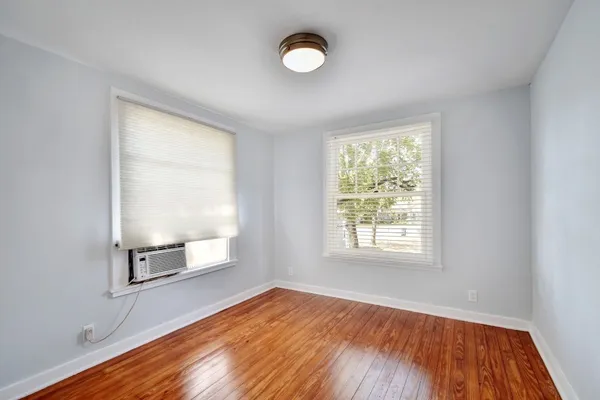 an empty room with wooden floor cabinet and windows