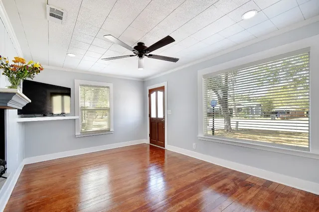 a view of an empty room with a window and wooden floor