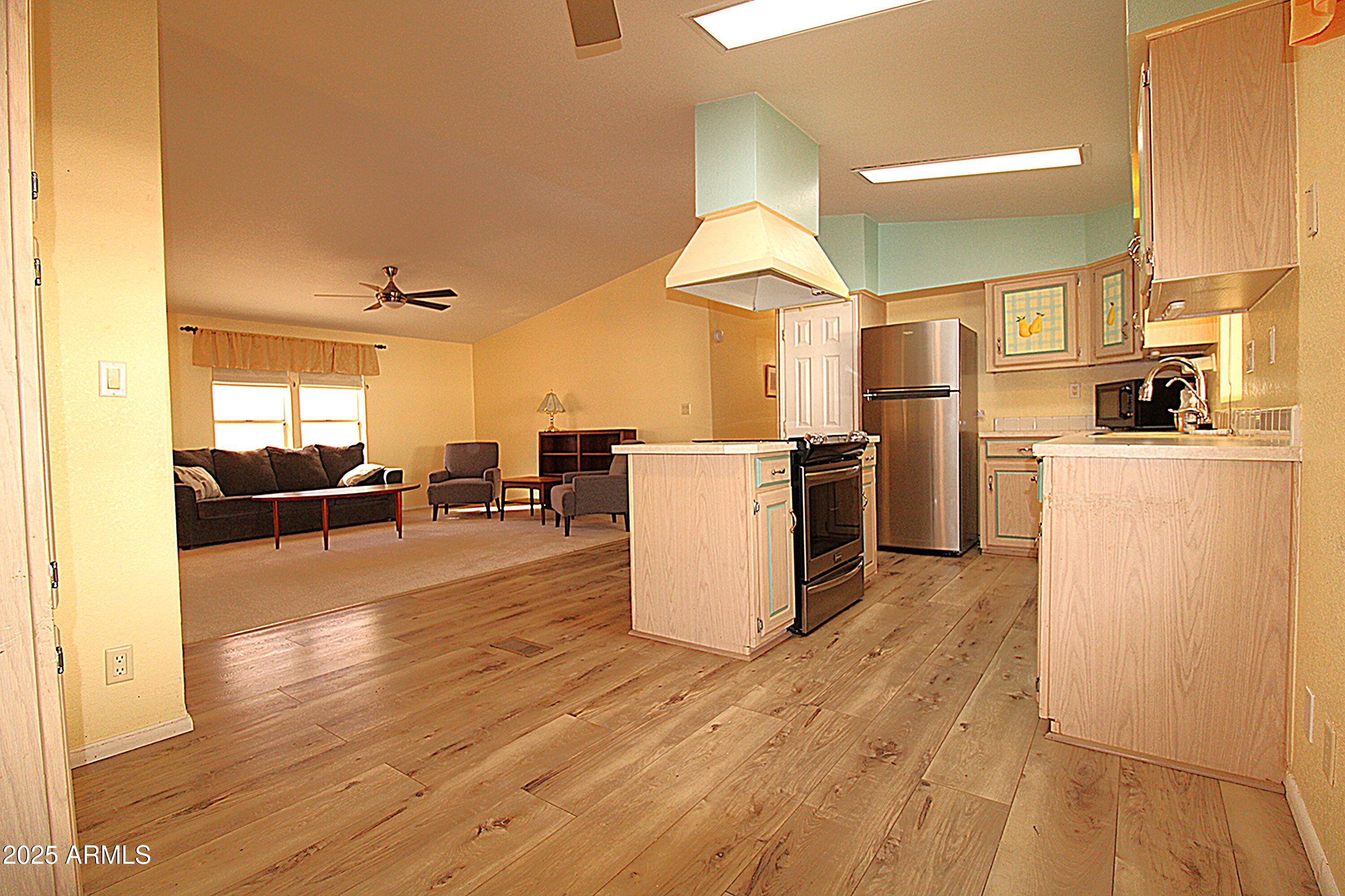 2400 East Baseline Avenue, Unit 232 Apache Junction, AZ 85119 - Photo 12 of 37 a kitchen with a refrigerator wooden floor dining table and chairs