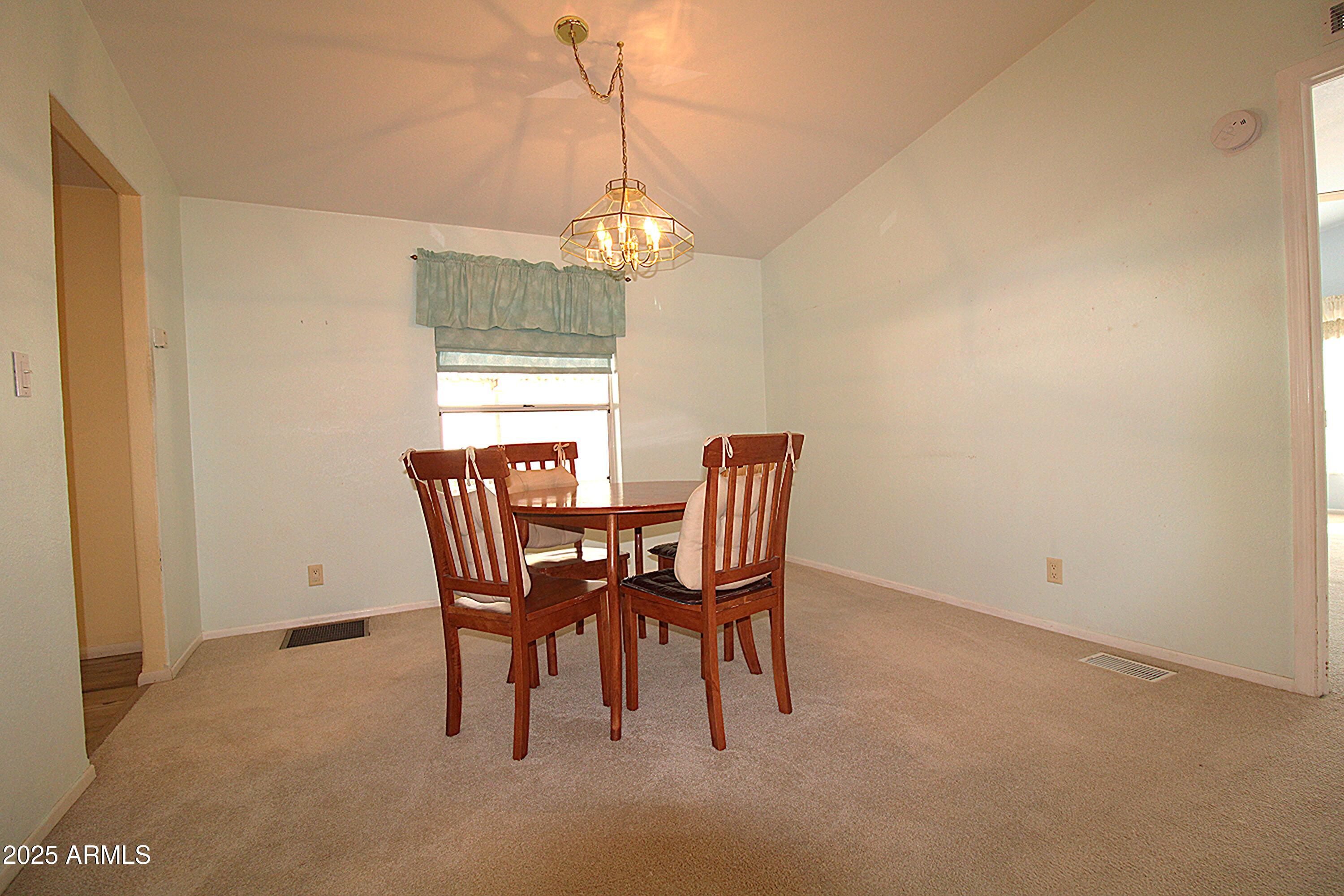 2400 East Baseline Avenue, Unit 232 Apache Junction, AZ 85119 - Photo 14 of 37 a dining room with furniture a chandelier and a window