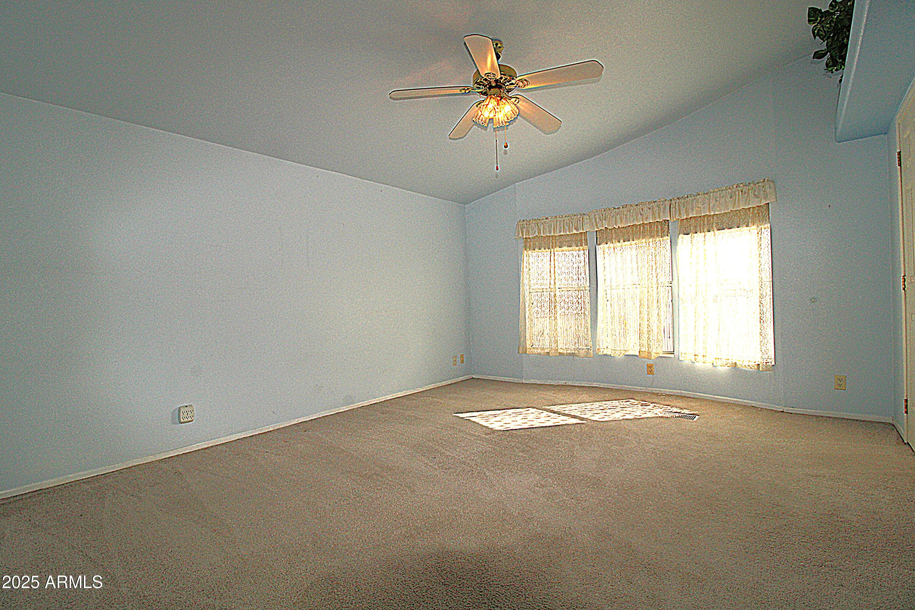 2400 East Baseline Avenue, Unit 232 Apache Junction, AZ 85119 - Photo 18 of 37 an empty room with a window and a ceiling fan