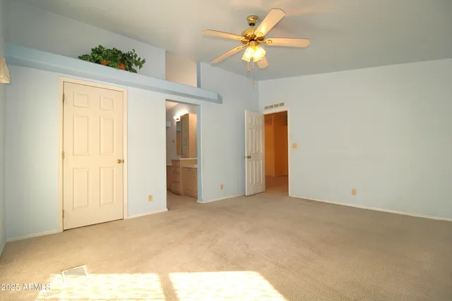 an empty room with closet and a chandelier fan