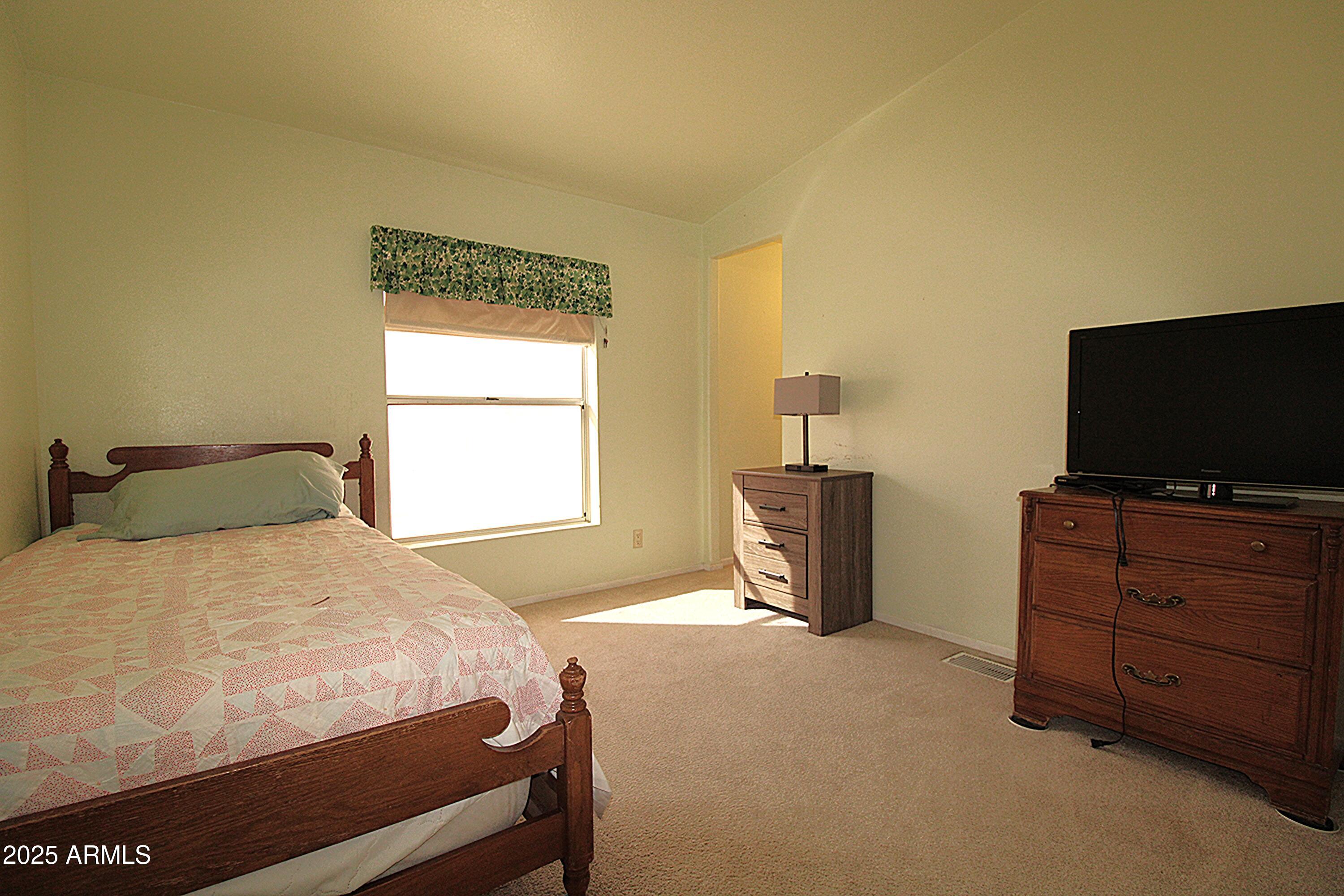 2400 East Baseline Avenue, Unit 232 Apache Junction, AZ 85119 - Photo 29 of 37 a bedroom with a bed and flat screen tv