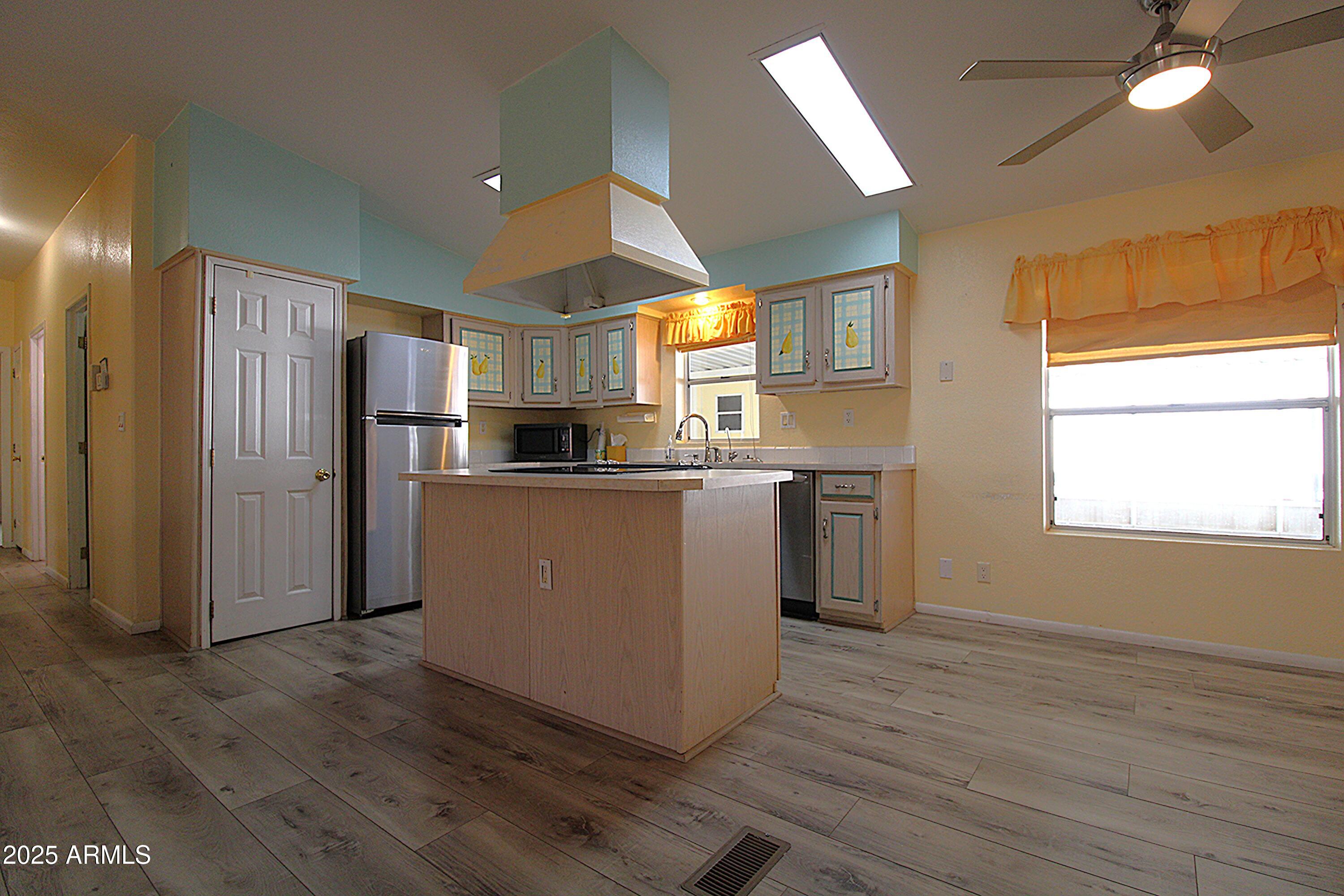 2400 East Baseline Avenue, Unit 232 Apache Junction, AZ 85119 - Photo 7 of 37 a kitchen with kitchen island wooden floors appliances and window