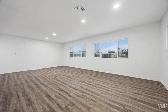 a view of an empty room with a window and wooden floor