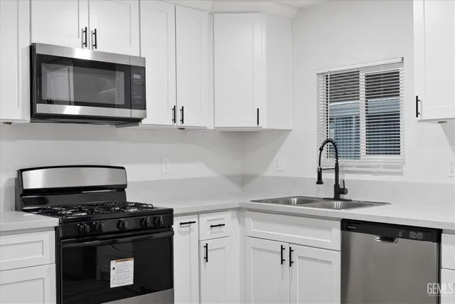 a kitchen with granite countertop white cabinets and stainless steel appliances