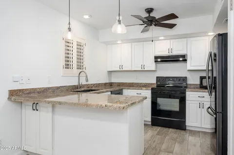 a kitchen with stainless steel appliances granite countertop a sink a stove a refrigerator and island with wooden floor