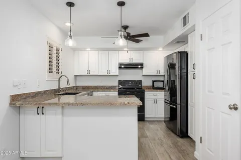 a kitchen with stainless steel appliances granite countertop a sink a stove a refrigerator and cabinets