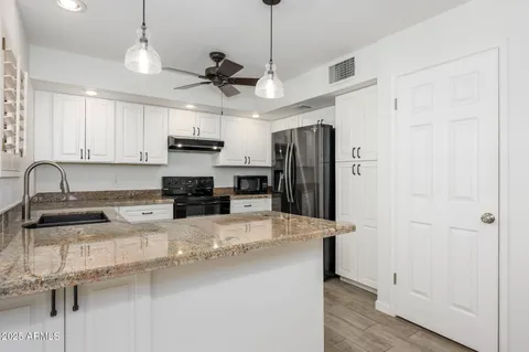 a kitchen with granite countertop a refrigerator a sink a stove a microwave and island with wooden floor