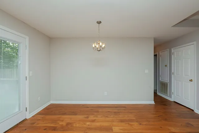 a view of an empty room with window and wooden floor
