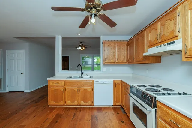 a kitchen with stainless steel appliances granite countertop wooden floors and white cabinets