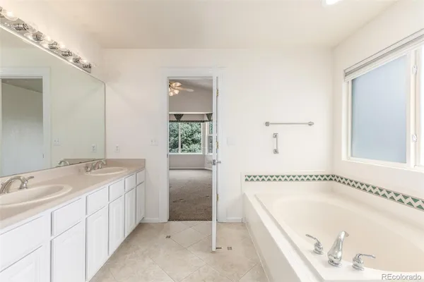 a spacious bathroom with a tub sink and mirror