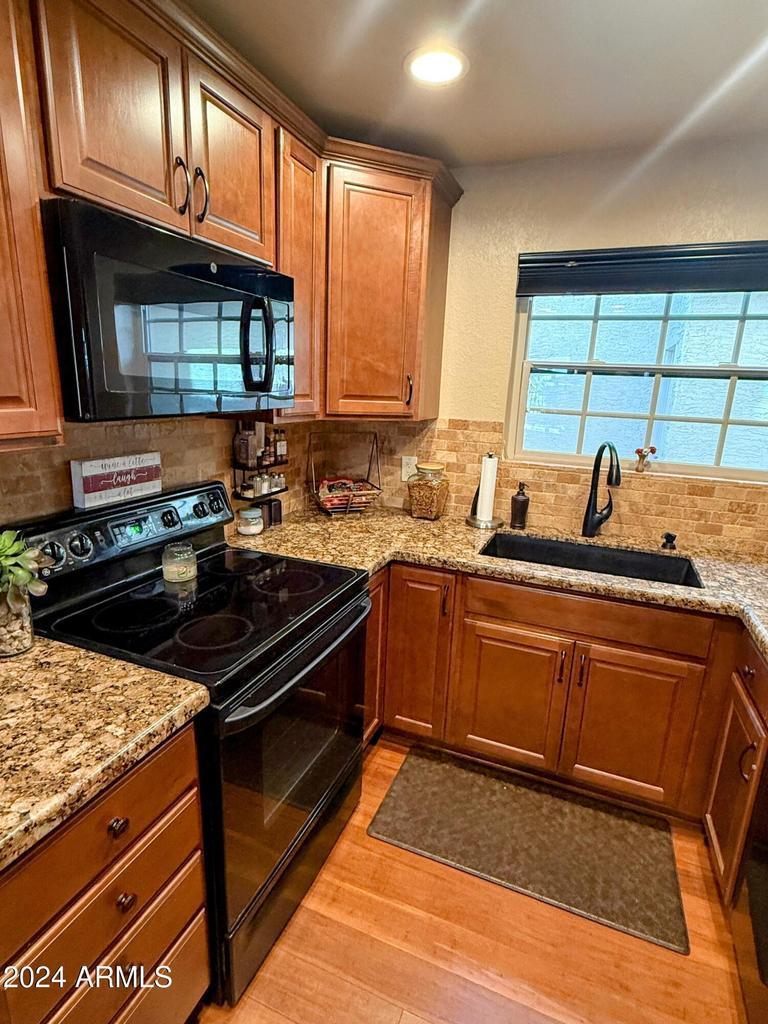 10015 East Mountain View Road, Unit 1002 Scottsdale, AZ 85258 - Photo 11 of 24 a kitchen with granite countertop a sink stove and cabinets