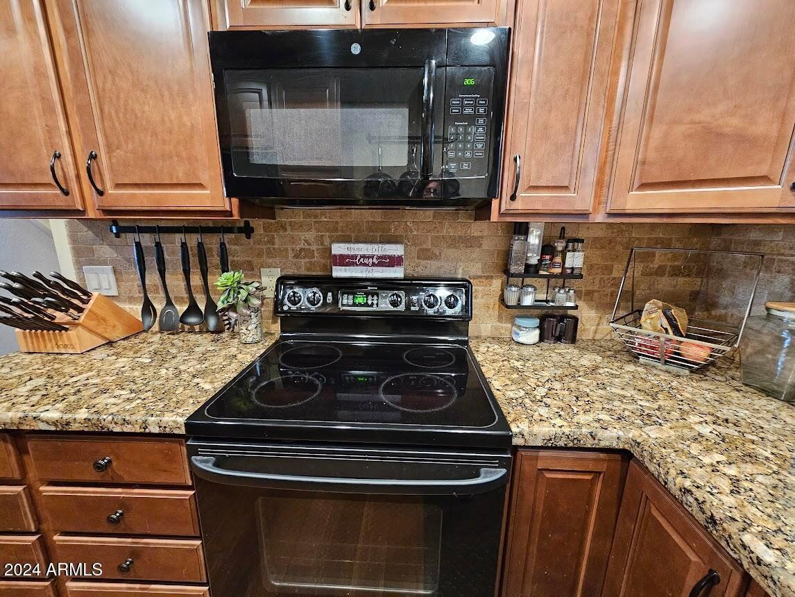 10015 East Mountain View Road, Unit 1002 Scottsdale, AZ 85258 - Photo 12 of 24 a kitchen with stainless steel appliances granite countertop a stove and a microwave
