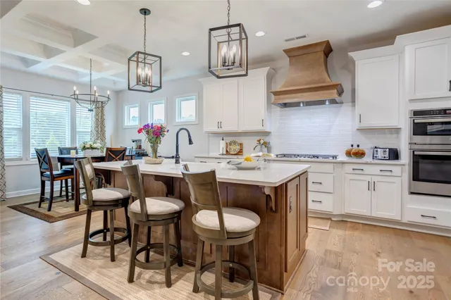 a kitchen with stainless steel appliances a stove a sink and chairs