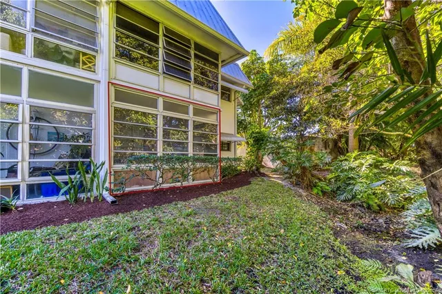 a view of yellow house with a yard and plants