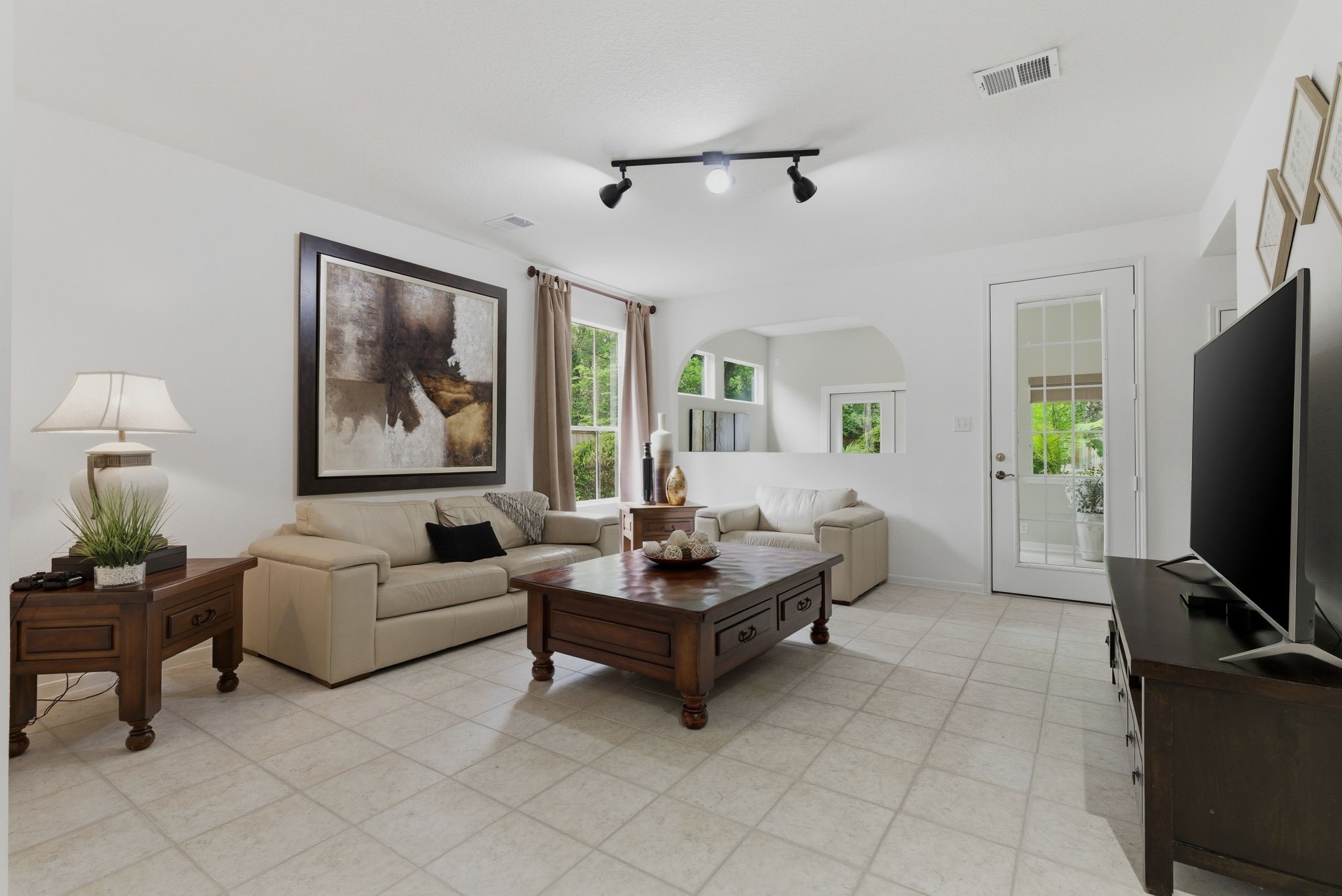 11 Dovewing Place Spring, TX 77382 - Photo 18 of 32 Spacious living room that flows into the stunning sunroom with ample natural light from large windows. There's a door leading outside, enhancing the indoor-outdoor flow.