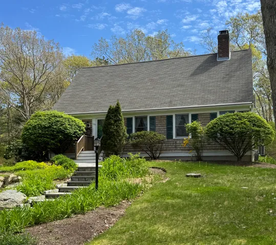 a view of a house with a yard and large tree