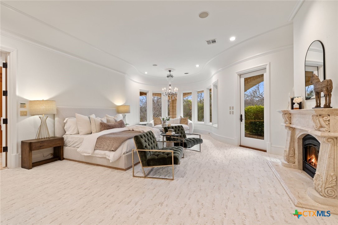 8536 Armstrong Road Belton, TX 76513 - Photo 12 of 41 a spacious bedroom with a bed a fireplace and a chandelier