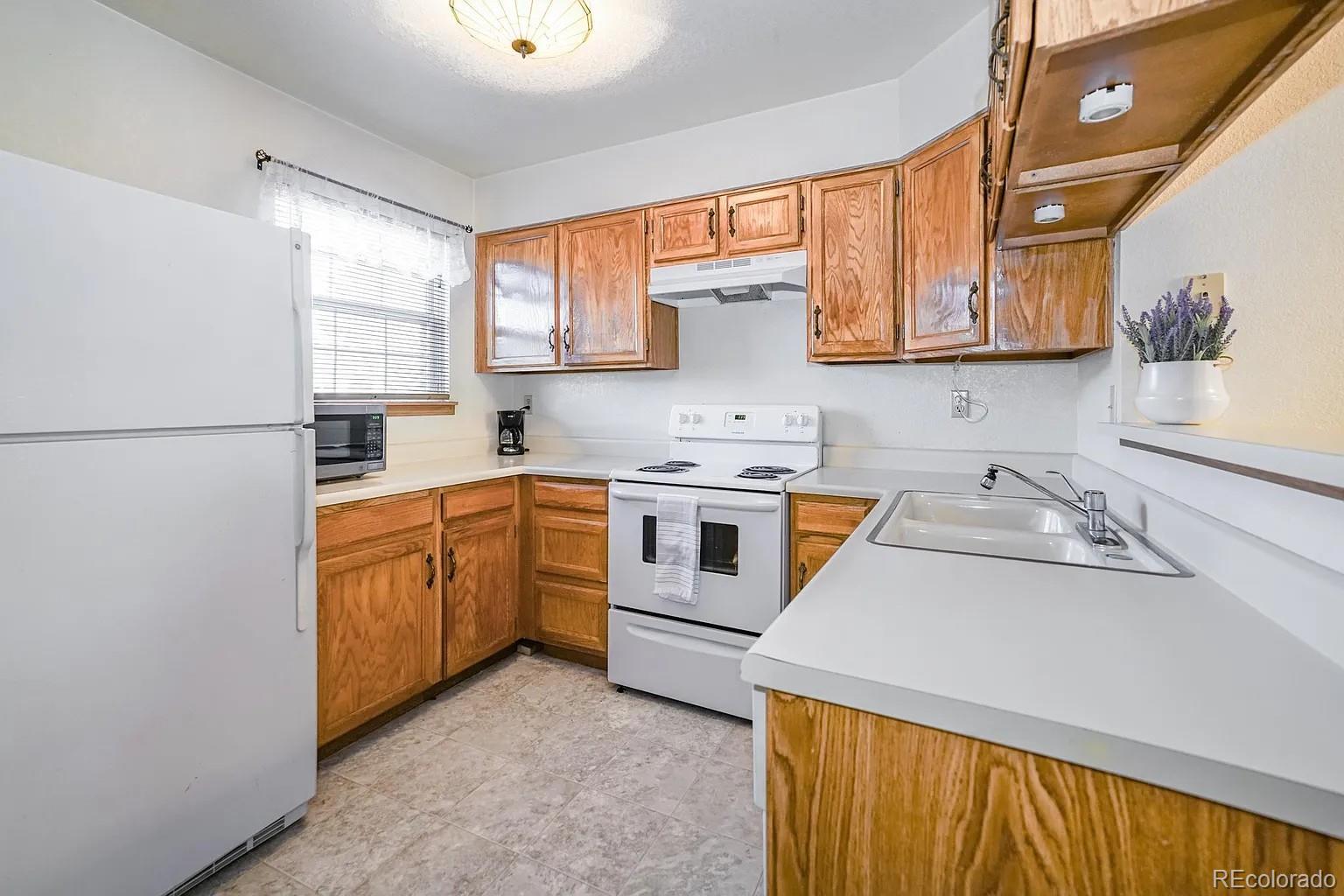 8280 South Fillmore Way Centennial, CO 80122 - Photo 4 of 10 a kitchen with stainless steel appliances granite countertop a sink a stove a refrigerator with grey cabinets