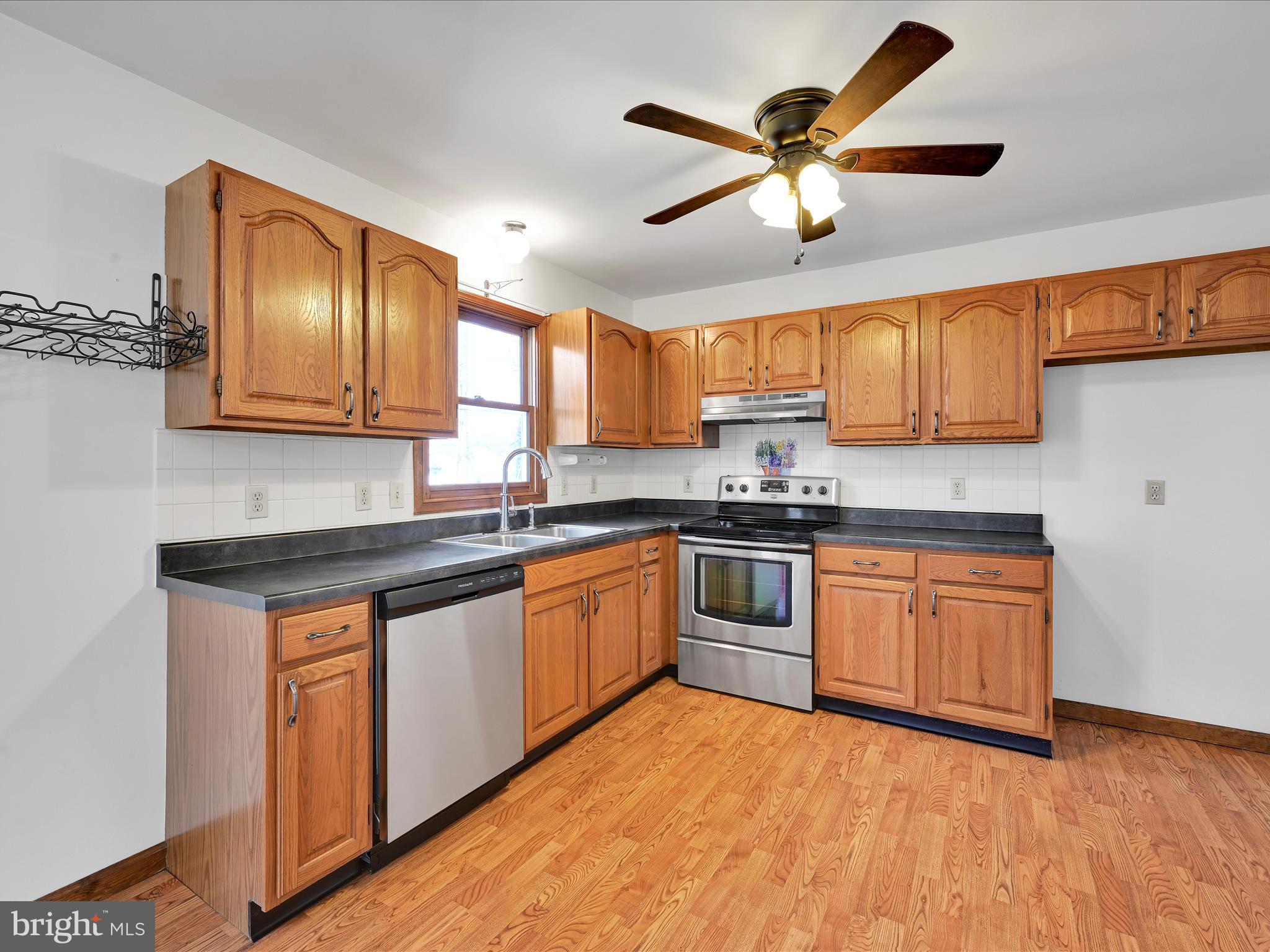 5 T-992 Stevens, PA 17578 - Photo 12 of 34 a kitchen with granite countertop wooden cabinets a sink a window and stainless steel appliances