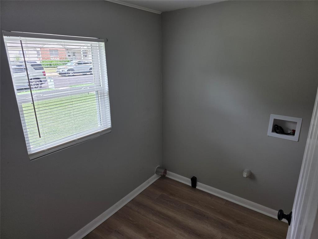 2804 Summer Avenue Waco, TX 76708 - Photo 13 of 13 Utility area featuring a window with white blinds, wood-finish flooring, light gray walls, and white baseboards