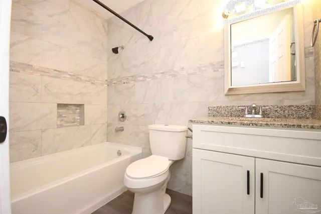 a bathroom with a granite countertop toilet a sink and a bathtub