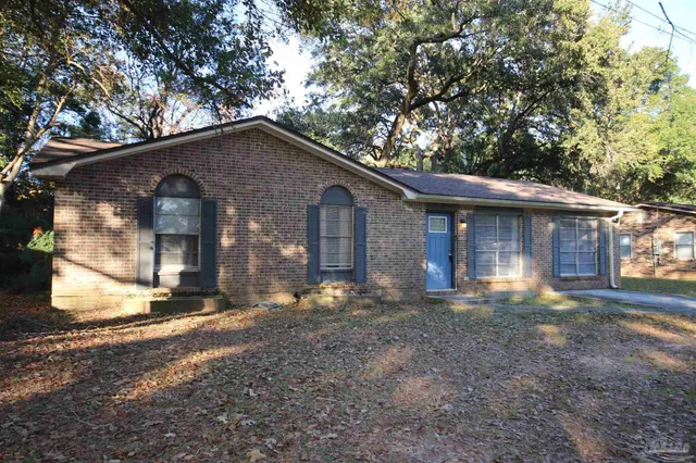 a front view of a house with a yard and large tree