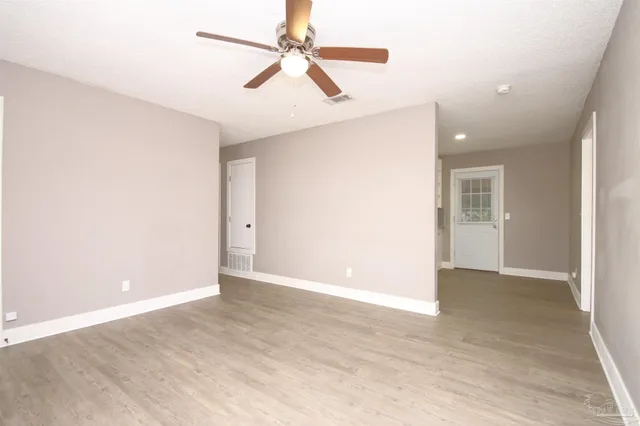 an empty room with ceiling fan and window