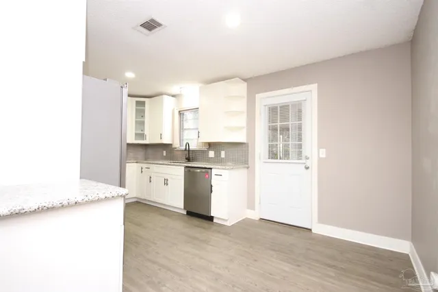 a kitchen with a refrigerator and white cabinets