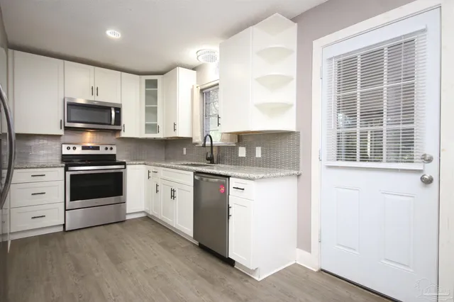 a kitchen with granite countertop a stove a sink and a microwave
