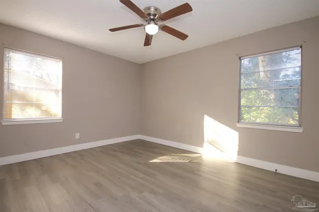 a view of a big room with wooden floor and windows