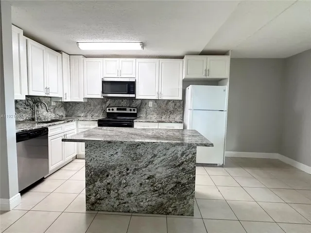 a kitchen with granite countertop a stove a sink and a refrigerator