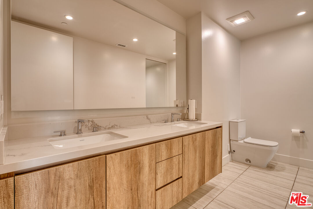 411 South Hamel Road, Unit 306 Los Angeles, CA 90048 - Photo 25 of 40 a bathroom with a granite countertop sink a toilet and a mirror