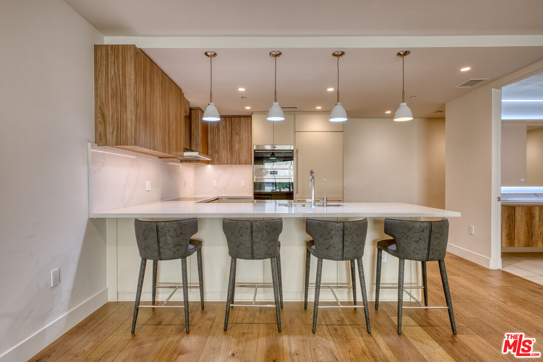 411 South Hamel Road, Unit 306 Los Angeles, CA 90048 - Photo 9 of 40 a kitchen with a table chairs refrigerator and microwave