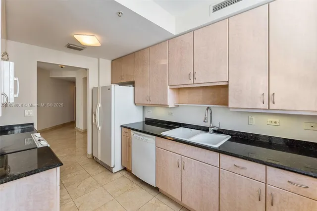 a kitchen with granite countertop a sink a stove and cabinets