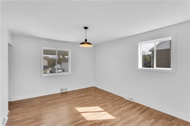 a view of an empty room with window and wooden floor